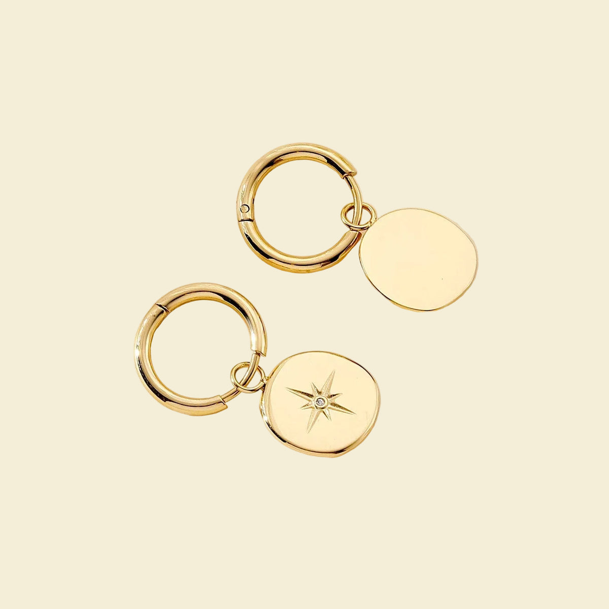 Gold-toned round drop earrings with a small starburst detail and a tiny clear stone, shown on a light beige background with measurement arrows and text indicating 2.8cm width and 1.
